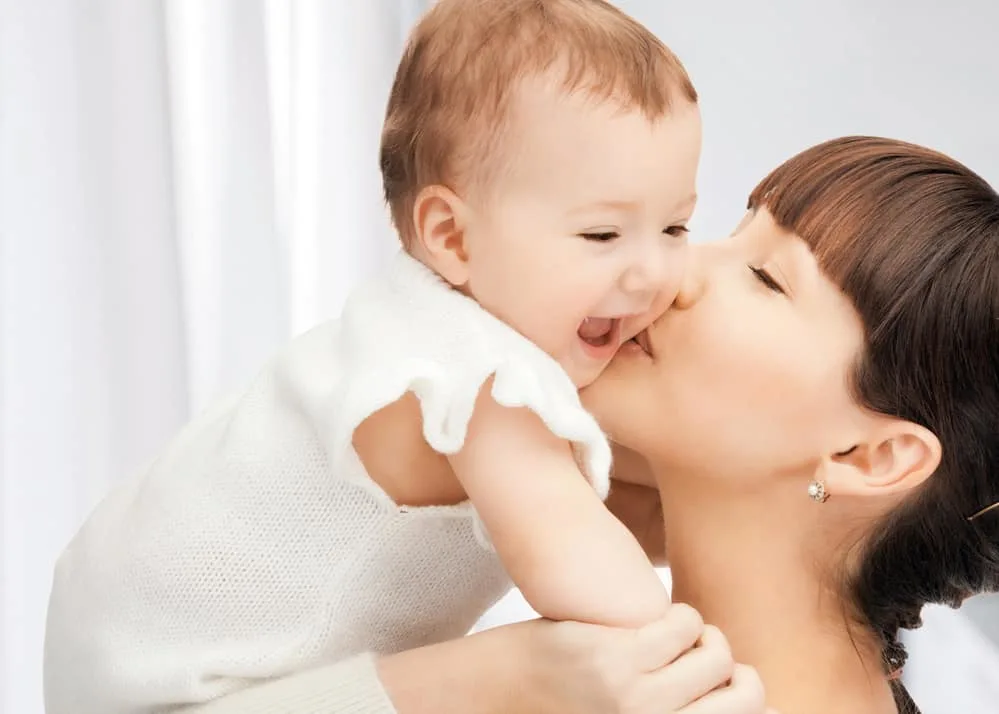 mom kissing baby on cheek